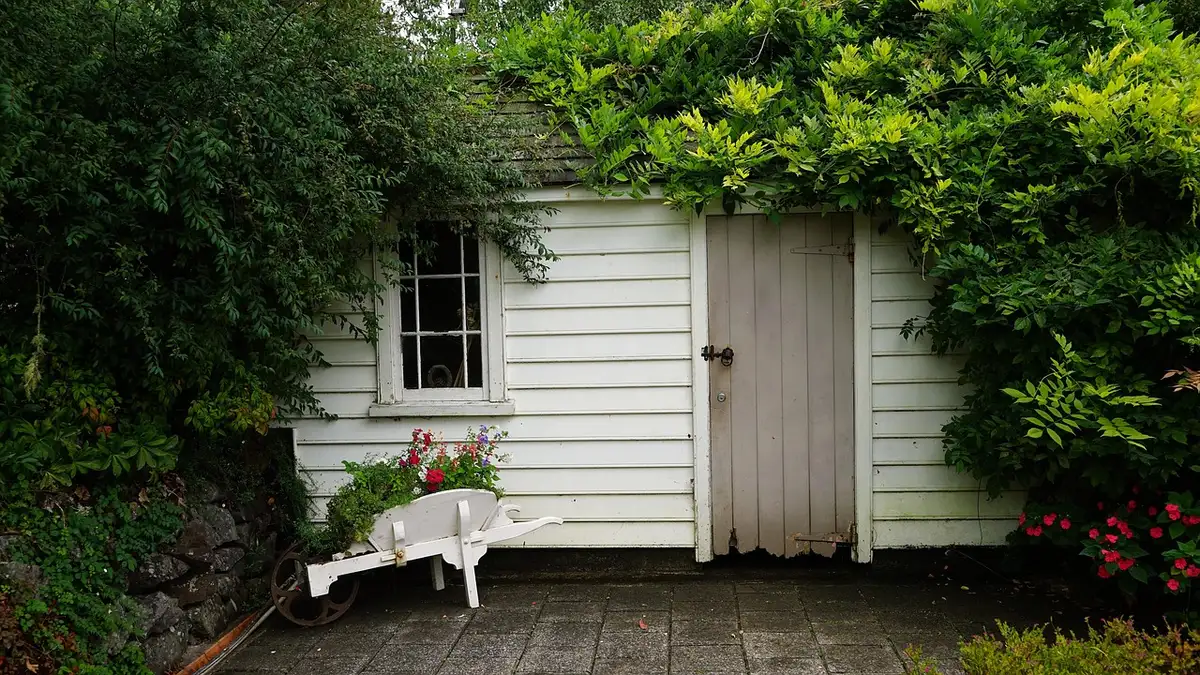 Daylit small garden shed interior with compact desk, shelving and folded exercise mat, no brand visible