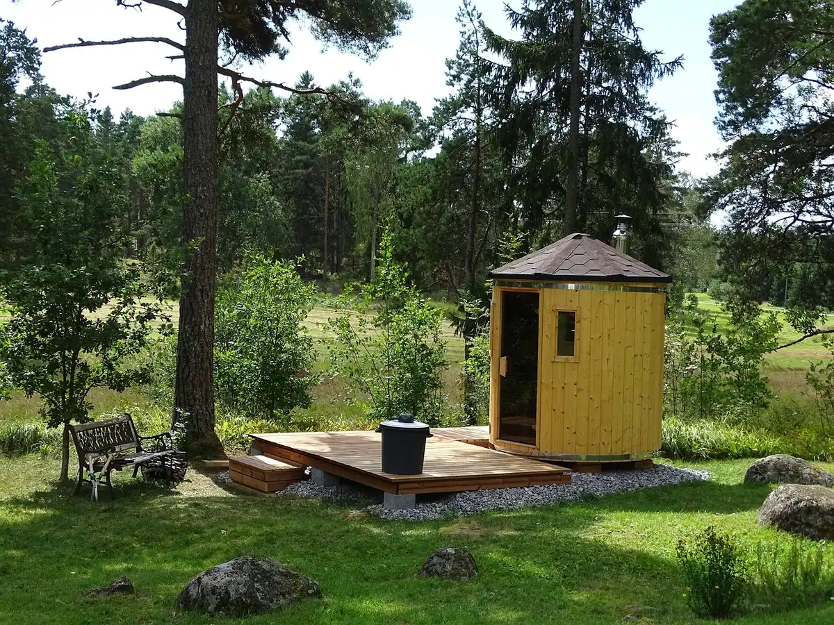 daylight garden corner with a small unbranded wooden cabin window open, potted plants on a bench, clean path