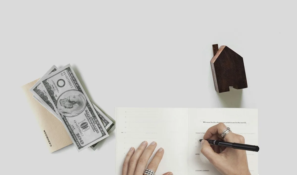 Hands filling a government form on a wooden table with building sketches and a tape measure nearby
