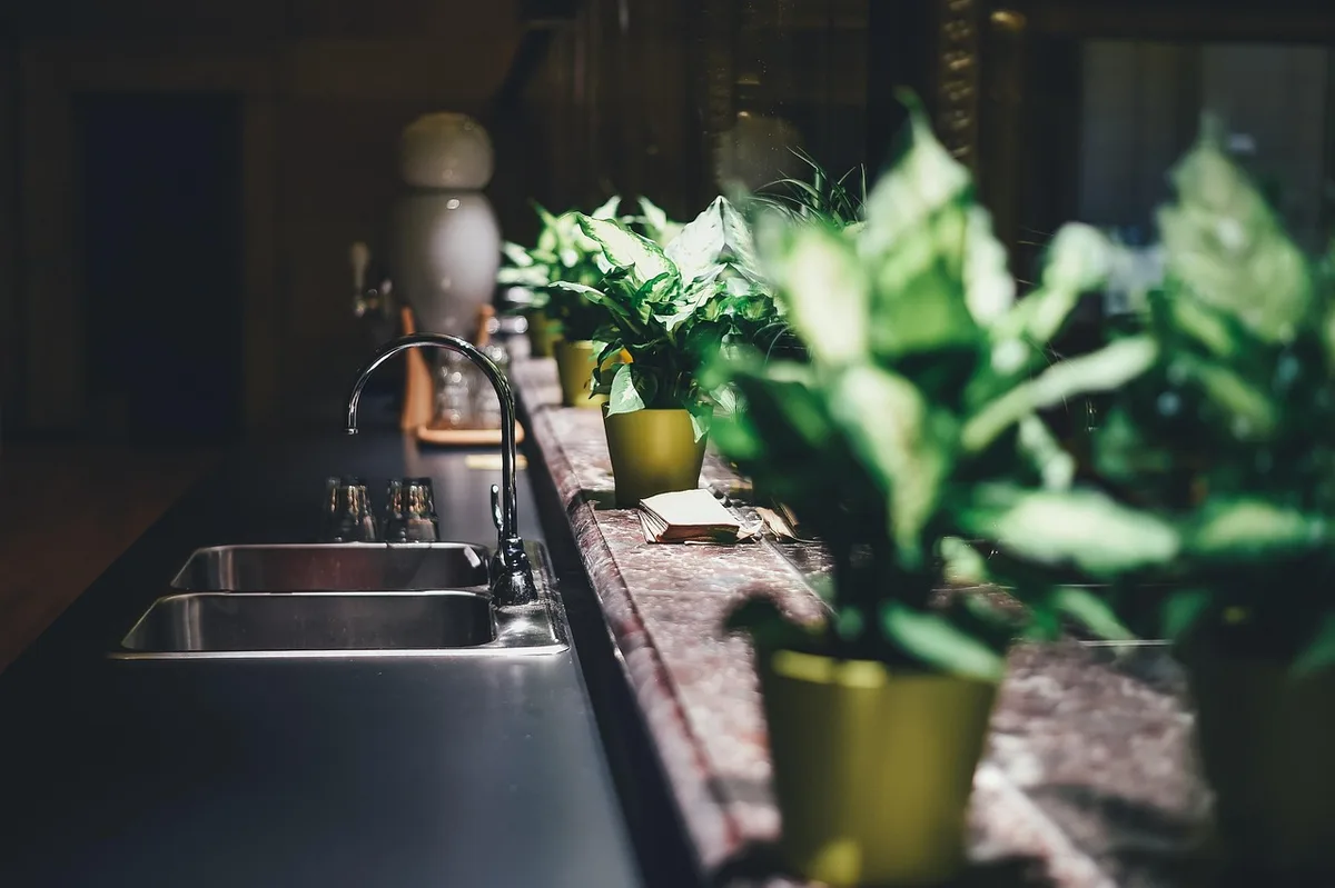 bright well-lit modern kitchen corner with unbranded cabinetry, sample swatches on a table, hands holding a material sample