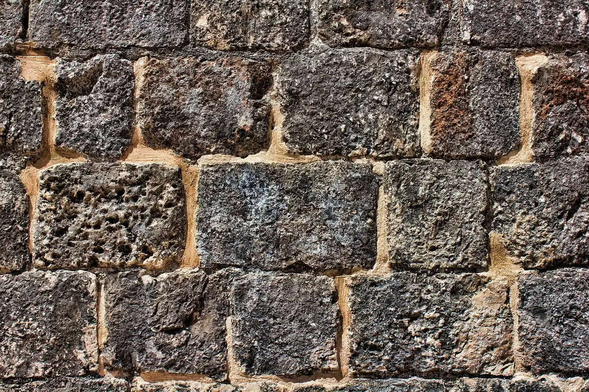 interior stone wall with narrow ventilated gap behind battens, tools on a bench