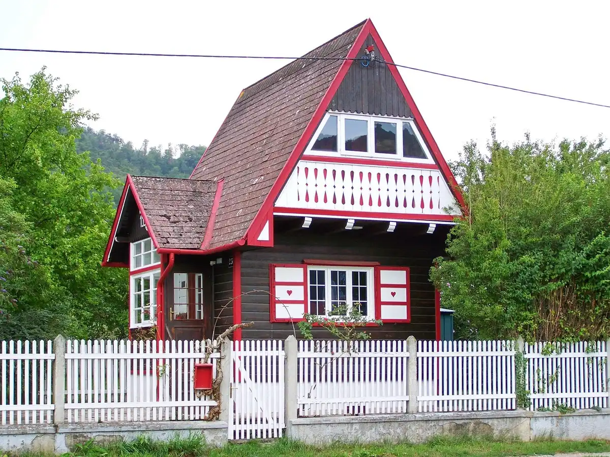 A neat daylight garden scene with a generic wooden garden chalet on a gravel base, no logos or people, tools and a potted plant nearby suggest preparation and home improvement
