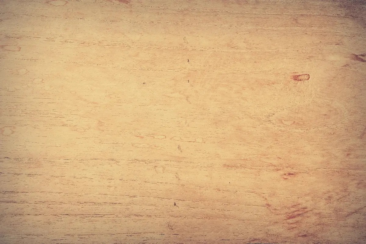 Close-up of a hands marking a plywood sheet on a workshop bench, cordless drill at side
