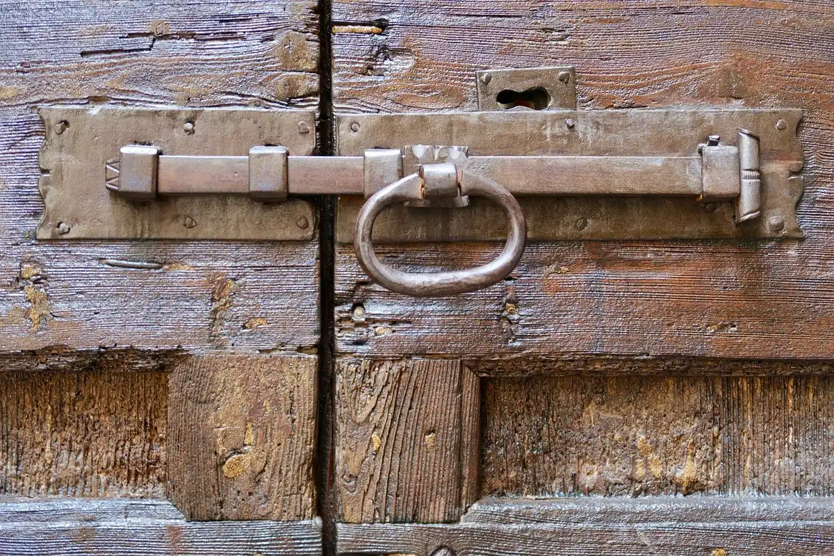 Close-up of a saw blade near the bottom edge of a wooden door lying flat on sawhorses, pencil cutting line visible
